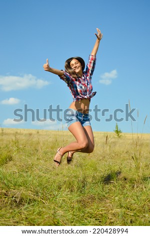 jumping joy: sexy pretty girl in jeans shorts running high and happy smiling on blue sky outdoors copy space background, portrait