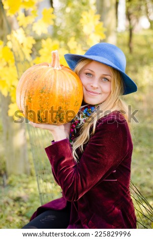 portrait of holding pumpkin elegant beautiful blond young woman having fun happy smiling and looking at camera on autumn copy space outdoors background