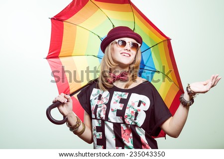 Studio portrait of teenage hipster girl wearing trendy hat and sunglasses with colorful umbrella over olive copy space background