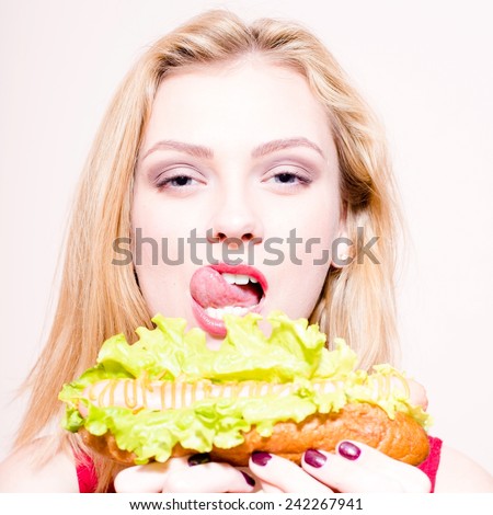 closeup of eating tasty hot-dog happy blonde sexy woman with blue eyes having fun flirting smiling and looking at camera on white background