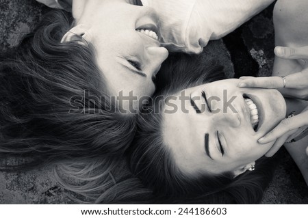 closeup picture of happy girl friends relaxing head to head happy smiling