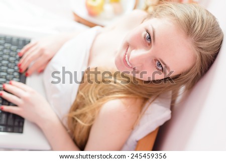 beautiful young business woman sitting in bed with laptop computer happy smiling looking at camera, closeup portrait