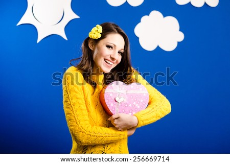 Portrait of amazing young beautiful lady in yellow sweater hugging heart shaped present box