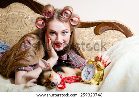 Portrait of beautiful young lady having fun happy smile relaxing lying in bed with clock and her dog