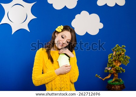 Portrait of happy smiling pretty girl in yellow sweater with arrow or house