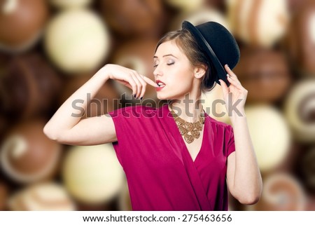 Portrait of elegant beautiful young woman in hat dreaming with closed eyes on blurred candies background