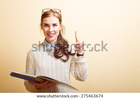 Portrait of beautiful young lady in glasses holding papers or books and pointing up