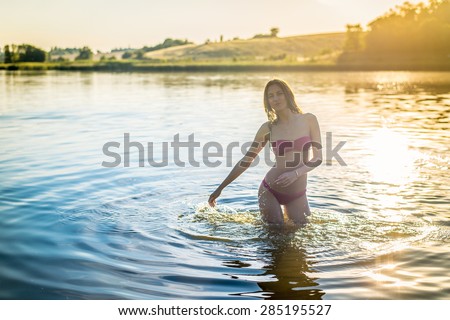 Portrait of joyful sexy beautiful young lady in great fitness shape happy smiling and having fun in the lake on green summer outdoors