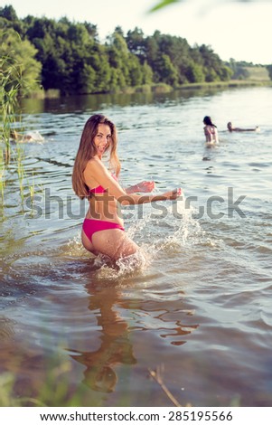 Portrait of joyful sexy beautiful young lady in great fitness shape happy smiling and having fun in the lake on green summer outdoors