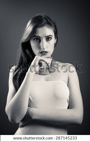 Black and white close up portrait of beautiful young woman posing in studio on dark  background