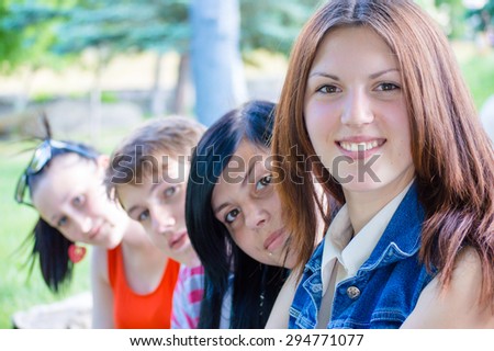 Portrait of group of four young people looking at camera on outdoors background