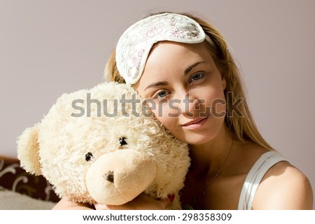 Woman blue eyes with sleep bandage hugging teddy bear
