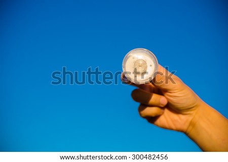 LED lamp in hand against blue sky