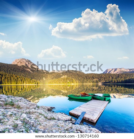 Reflection in water of mountain lakes and boats. Black lake in Durmitor national park in Montenegro, Europe. Beauty world.