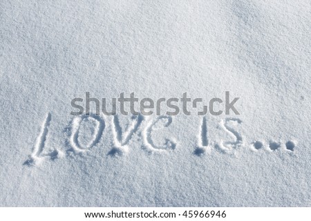 writing text LOVE IS on the snow