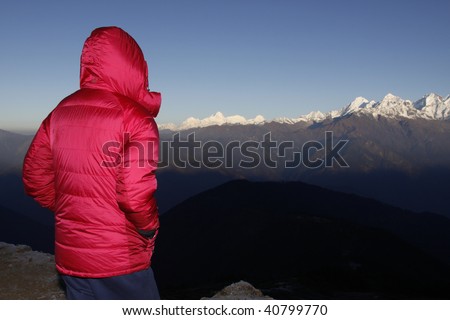 Girl in down coat watching the sunrise on the mountains. Nepal