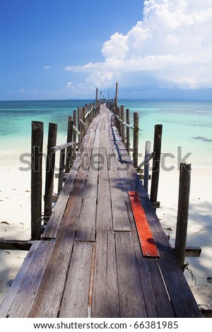 Tropical jetty leading out to the clear sea.