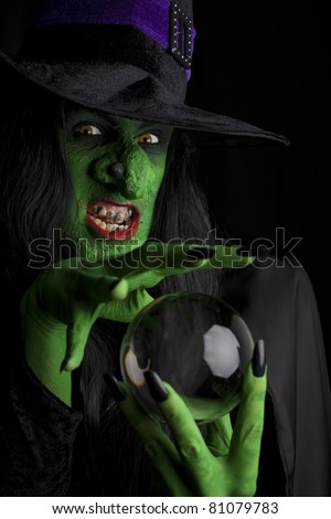 Evil witch looking into her crystal ball, black background.