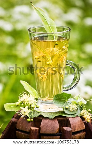 A cup of linden tea with linden flowers outdoors