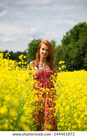 Young beautiful woman in the yellow rape field