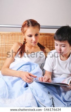 Mother reads bedtime story to young boy at night