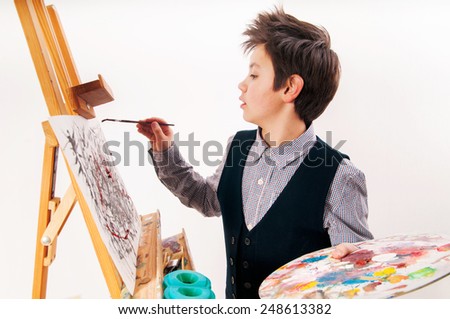 artist school boy painting brush watercolors portrait on a easel