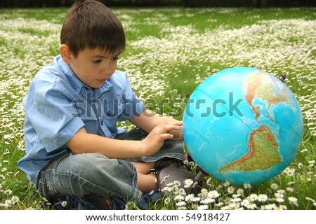 Schoolboy with globe on the grass