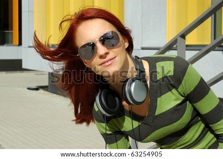 The girl in sun glasses listens to music through ear-phones