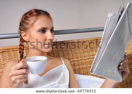 The young woman in bed at breakfast reads the newspaper
