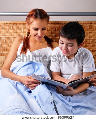 Mother reads bedtime story to young boy at night