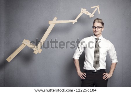 Concept: Positive business outlook. Smiling confident businessman with business vision in front of upwards pointing business graph, isolated on grey background.