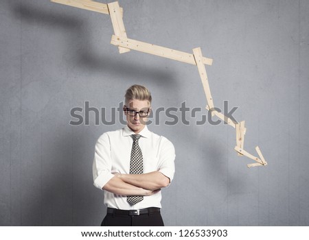Concept: Business failure. Miffed irritated businessman in front of business graph pointing down, isolated on grey background.
