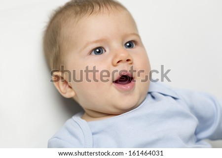 Close up portrait of adorable happy baby boy with blue eyes and mouth open.