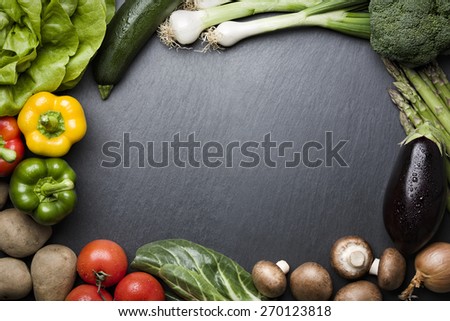 Arrangement of mixed colorful vegetables, isolated on dark gray slate stone background with empty copy space.