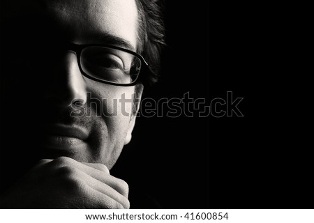 Close-up of young content man resting chin on fist, low key, black and white