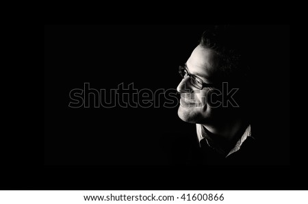 Close-up of young confident and happy man, low key, black and white