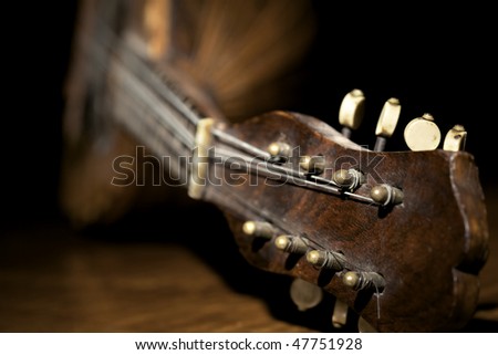 Closeup of old mandolin lying on wooden board and black background.