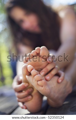 Young woman sitting on floor touching her feet to stretch.