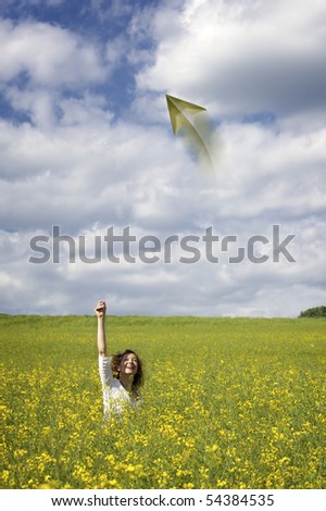Smiling woman in yellow rapeseed field throwing  a paper plane.