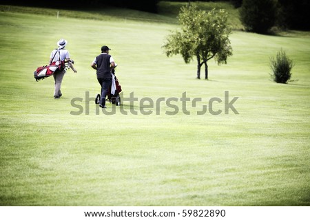 Two male golf player walking on fairway with their golf bags, plenty of copy-space.