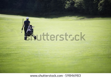 Female golf player walking on fairway with her golf bag, plenty of copy-space.