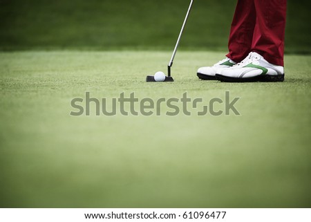 Feet of female golf player putting at green, with plenty of copy-space.
