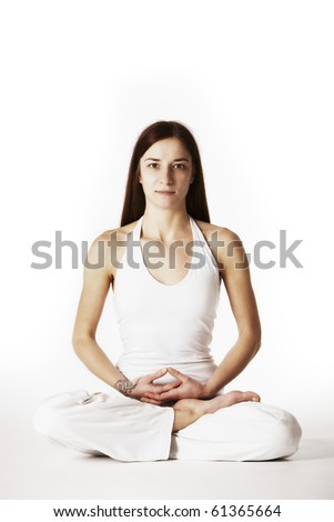 Young lady practicing yoga in lotus posture (Padmasana) in white clothes on white background, high-key image.