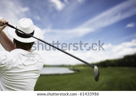 Close-up of male golf player with hat teeing-off at beautiful golf course.