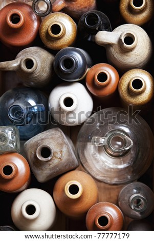 Collection of old colorful ceramic and glass wine and water bottles, top view.