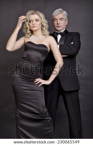 Beautiful woman and a brutal man in black robes standing on a dark background