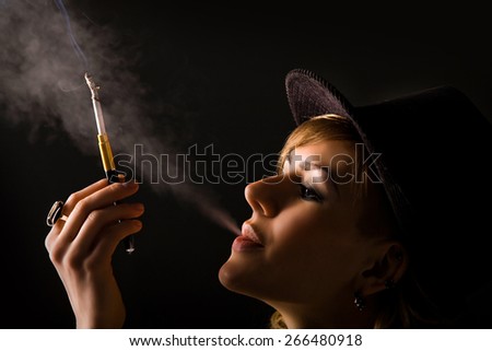 portrait of a beautiful girl in a dark room smoking a cigarette with a mouthpiece