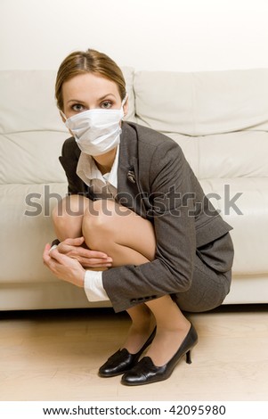 young woman wearing protective mask crouching fearful