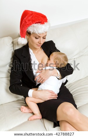 happy mother in business suit and santa hat breastfeeding baby