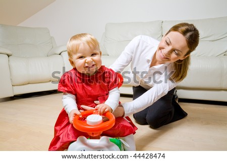 happy young mother with her baby daughter on a toy bicycle